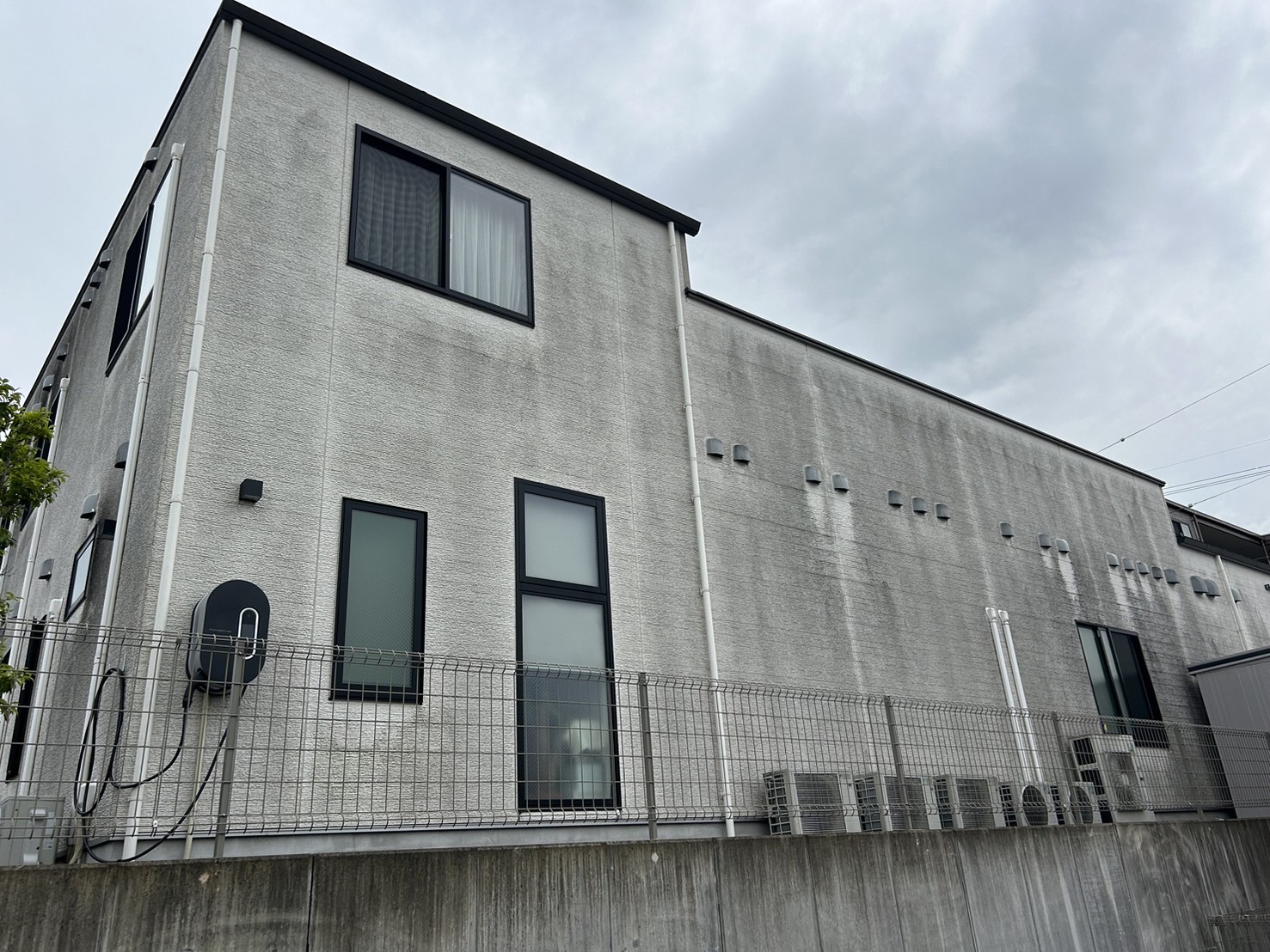 築8年医療施設の掃除前。排気ガスによる蓄積汚れを建物診断で特定。セルフ洗浄では落としきれなかった黒ずみが目立つ、専門的な掃除が必要な建物の外壁洗浄前の状態。