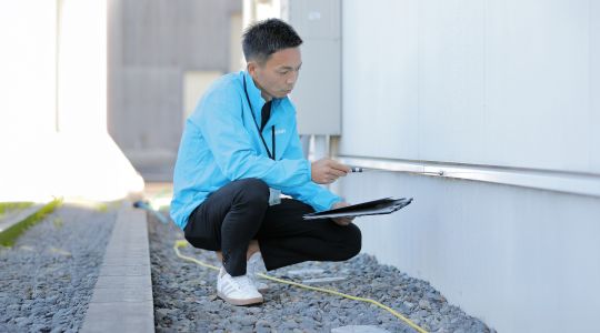外壁洗浄専門店WASHERS（ウォッシャーズ）による高度な建物診断。外壁診断士が、表面的な汚れだけでなく目に見えない内部の状態まで専門家の知見で読み解き、掃除が必要な原因を厳格に特定する様子を表現。